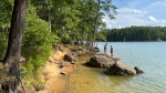 Two kids on giant boulders sticking out of the blue water of the lake at Red Mountain State Park