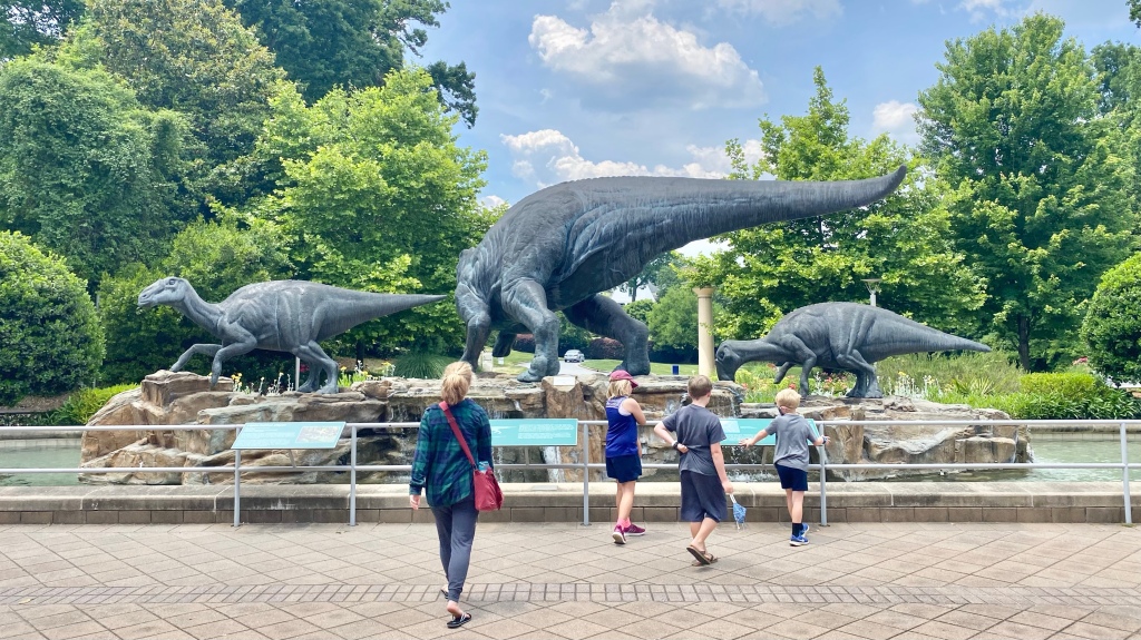 Four Kids approaching giant Dinosaur sculptures in the water feature at the Fernbank Museum in Atlanta